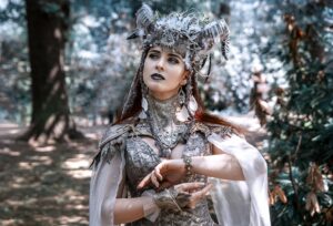 Woman in mystical costume posing gracefully in a serene forest setting.